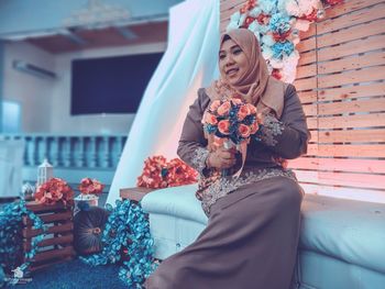 Smiling woman holding flower bouquet during celebration