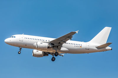 Low angle view of airplane flying against clear blue sky