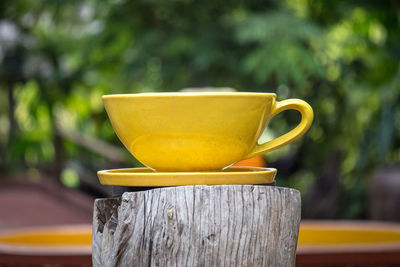 Close-up of yellow coffee cup on wooden post