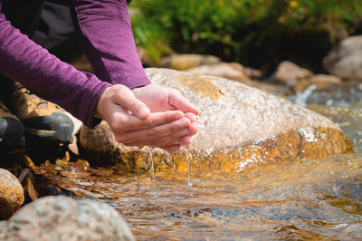 Close-up of water drops falling from female hands into a stream. the hand touches fresh water. a