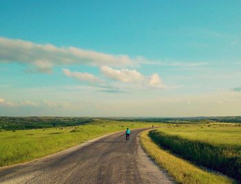 Rear view of man walking on road against sky