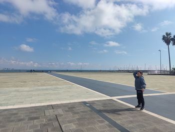 Rear view of man walking on beach against sky