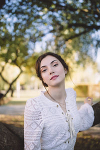 Portrait of young woman standing against trees