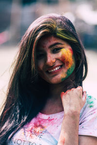 Portrait of smiling young woman with powder paint on face during holi