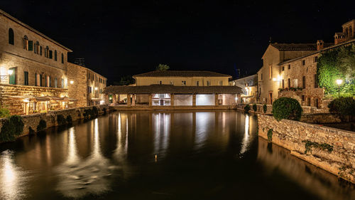 Bridge over canal amidst buildings in city at night