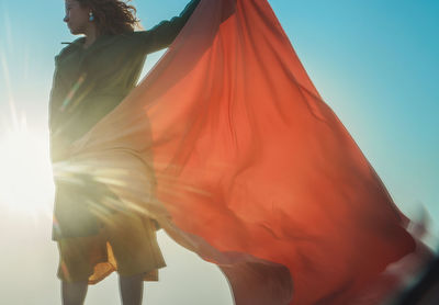 Low angle view of woman standing against blue sky