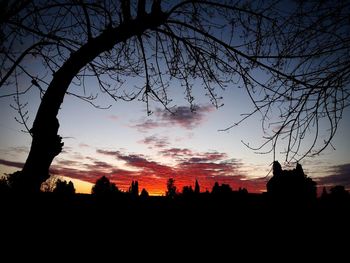 Silhouette trees and buildings against sky at sunset