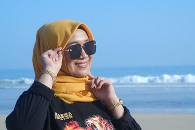 Young woman wearing sunglasses against sea