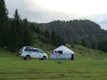 Car on field by mountain against sky