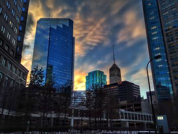 Low angle view of modern buildings against cloudy sky