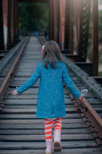 Rear view of girl walking on railroad tracks