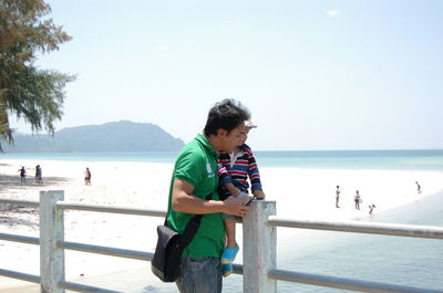 Father with son standing against sea