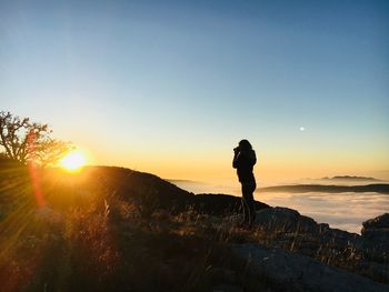 Silhouette woman standing on mountain against sky during sunset