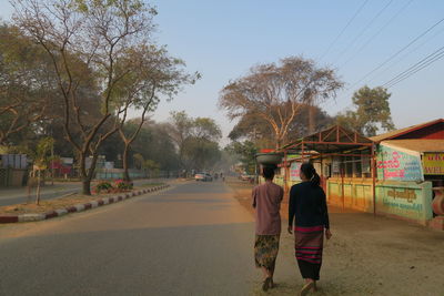 Rear view of women standing on road