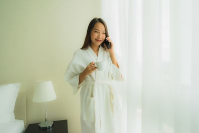 Young woman using phone while standing at home