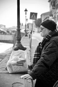 Side view of man holding umbrella on street