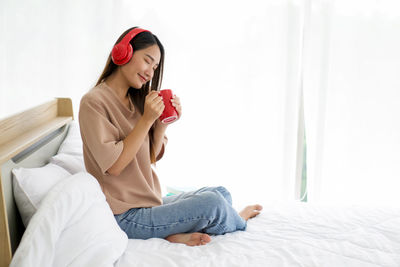 Young woman sitting on bed at home