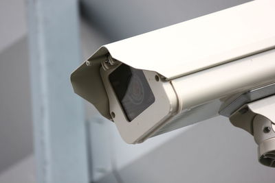 Close-up of security camera against white wall