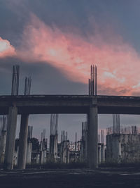 Bridge by buildings against sky during sunset