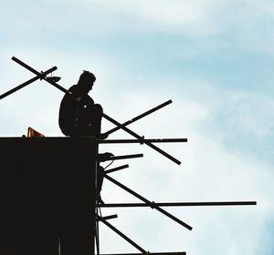 Man in silhouette siting on top of scaffolding