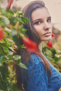 Side view portrait of beautiful woman standing by flowering plant