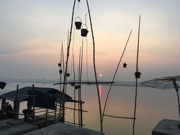 Clothes hanging on beach against sky during sunset