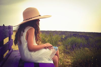 Midsection of woman sitting on field against sky