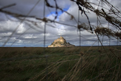 Panoramic view of  mont saint michel through a grid fence