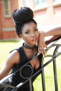 Portrait of young woman standing by railing