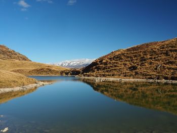 Scenic view of lake and mountains against clear blue sky