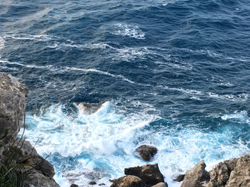 High angle view of waves splashing on rocks