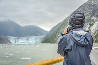 Rear view of woman standing by railing on boat