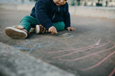 Low section of boy drawing on floor