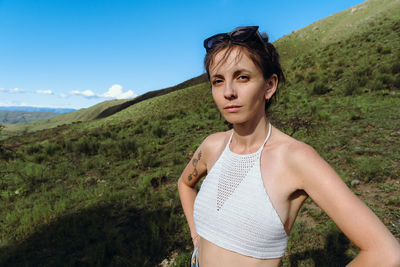 Portrait of young woman standing on land against sky