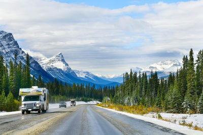 Road by snowcapped mountains against sky