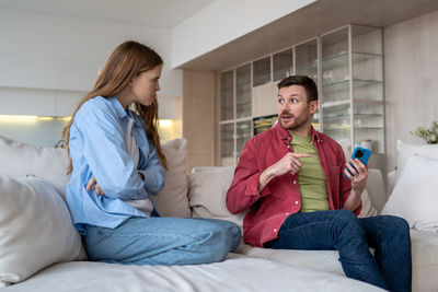 Young woman using mobile phone while sitting on bed at home