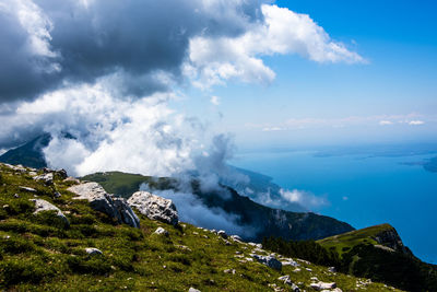 View of lake garda between rocks, clouds and blue sky on monte altissimo di nago in trento, italy