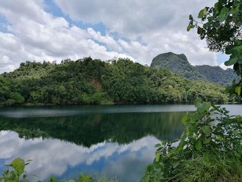 Reflection of trees in lake against cloudy sky