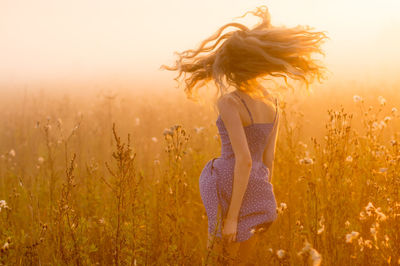 Midsection of woman on field against sky during sunset