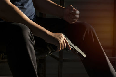 Midsection of man holding gun