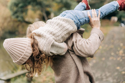 Happy young mother and little daughter fooling around outside in autumn.