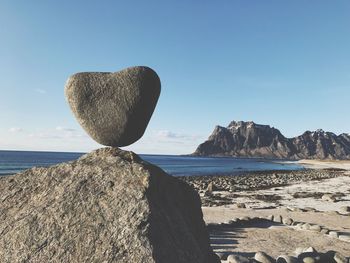 Heart shaped rock on beach against clear sky