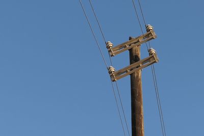 Low angle view of telephone lines against clear blue sky