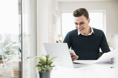 Young woman using mobile phone while sitting on table