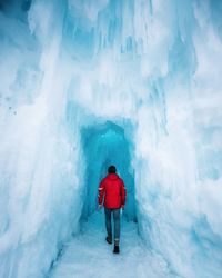 Rear view of man walking in glacier