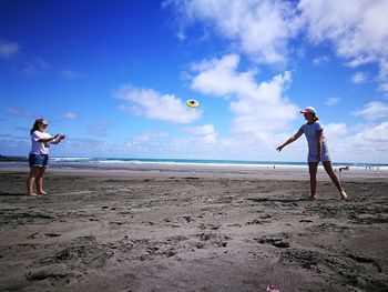 People playing on beach against sky