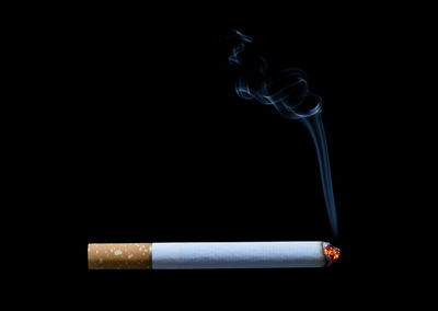 Close-up of cigarette smoking against black background