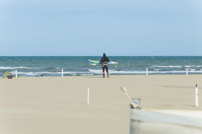 Rear view of man with surfboard walking at beach