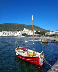 Sailboats moored on sea against clear blue sky