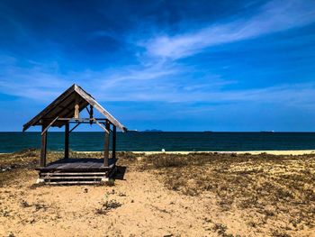 Old hut on beach against blue sky